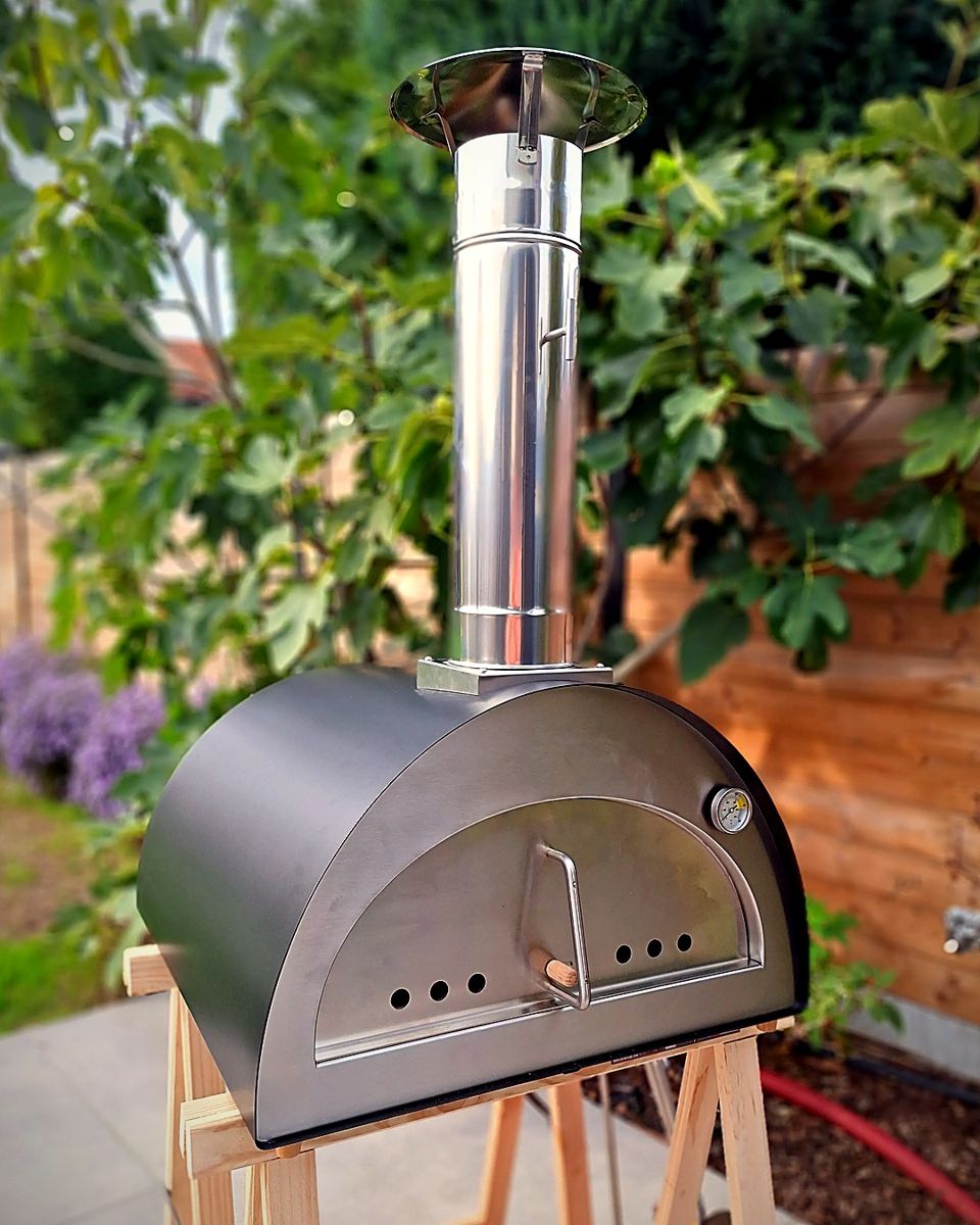 Houtgestookte pizzaoven op houten schragen in de tuin